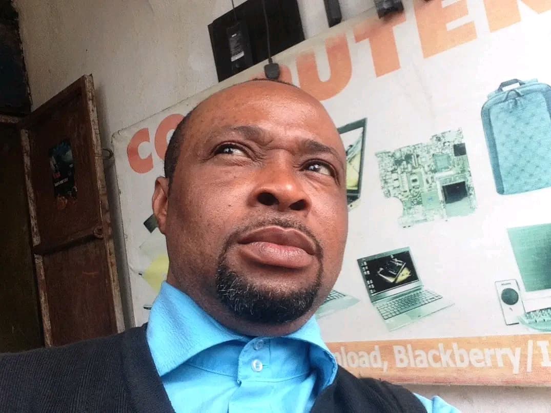 Kelechi, CEO of Kc Computers, smiling confidently in a professional setting. The background suggests an office or business environment. The mood is positive and successful.