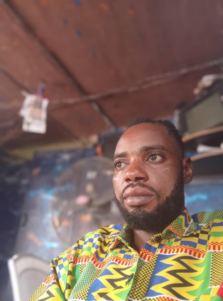 Atum Chikwado, CEO of D blue Elite Services, smiling confidently in a business setting. The background suggests a professional office environment. The mood is positive and reflects satisfaction and trust.